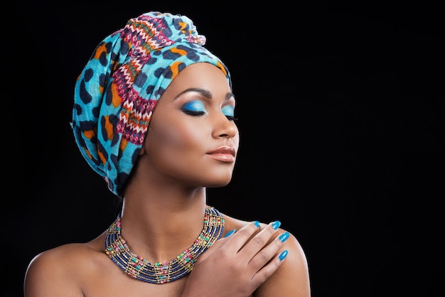 African beauty. Beautiful African woman wearing a headscarf and necklace keeping eyes closed 