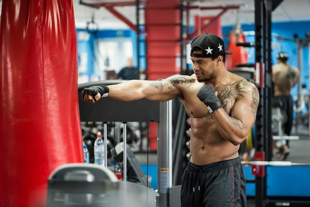 African black male boxer punching ball wearing boxing gloves in gym