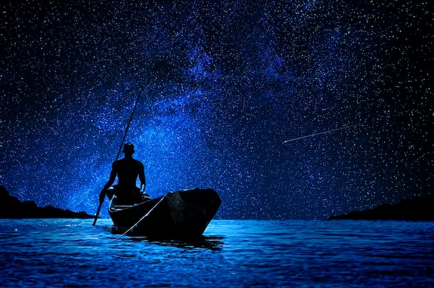Foto barcaiolo africano con la sua canoa davanti alle stelle
