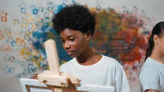 Photo african boy painting canvas while girl draw cool tone picture edification