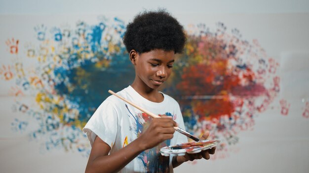 African boy standing while holding brush and point at camera art edification