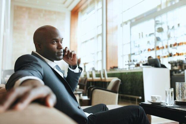 African business man talking on mobile phone while waiting in a
hotel lobby young business executive using cell phone while waiting
at lounge