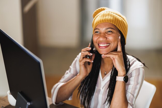Foto donna d'affari africana che usa un cellulare mentre fa una pausa mentre lavora a casa.