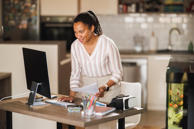 Африканская деловая женщина работает за компьютером в домашнем офисе.