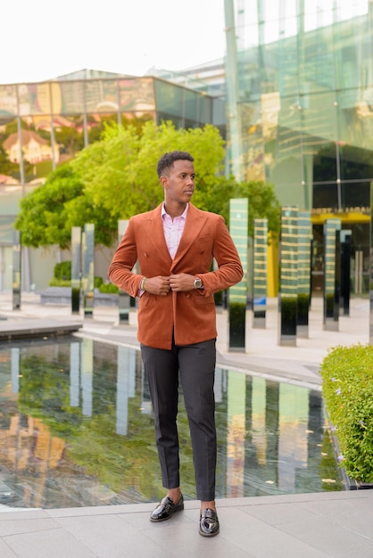 African businessman outdoors in city thinking full length shot