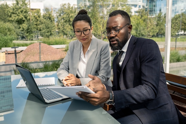 Photo african businessman showing paper to asian female partner