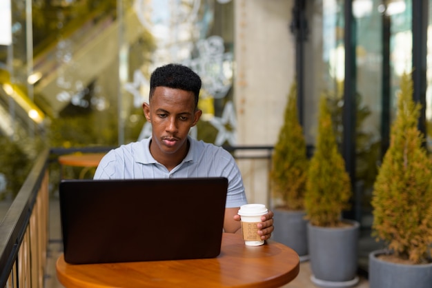 노트북 컴퓨터를 사용하는 동안 커피 숍에 앉아 아프리카 사업가