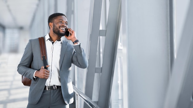 African Businessman Walking Inside Airport And Talking On Phone