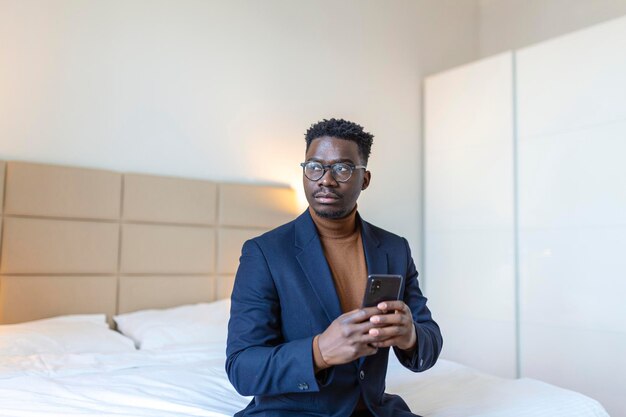 African businessman with smartphone in a hotel room Handsome man standing at the window texting Close up