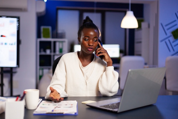 African businesswoman discussing with partner late at night from office