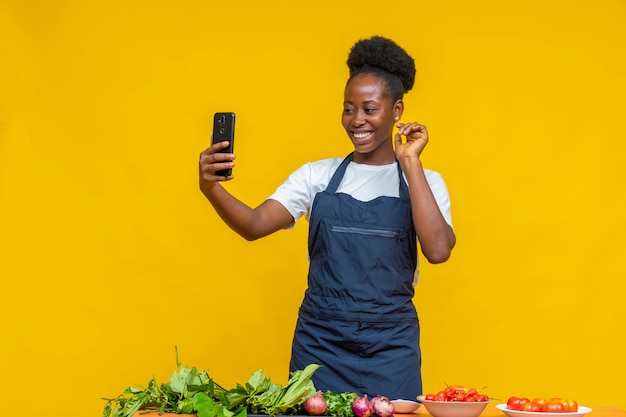 African chef doing video call, with cooking ingredients in front of her