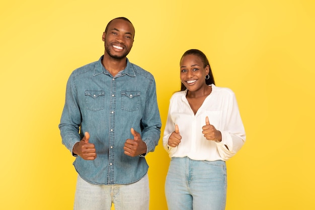 African Couple Gesturing Thumbs Up In Approval On Yellow Background