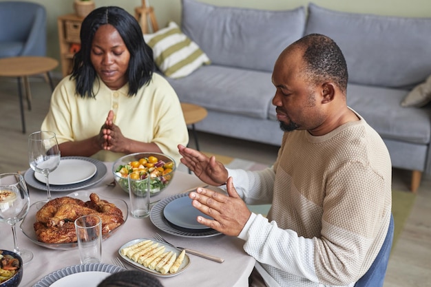 African couple praying at table