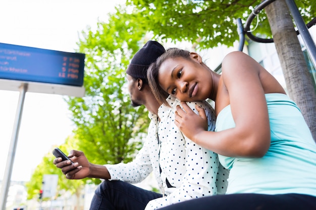 African couple waiting at bus station