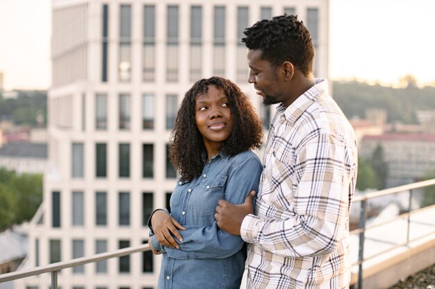 African couple woman and man hugging on rooftop of modern building