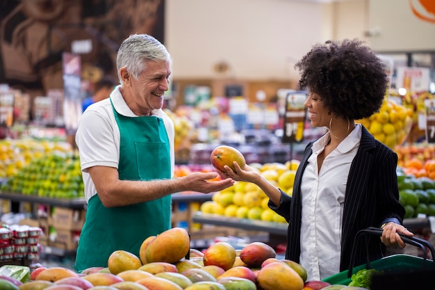 African Customer with greengrocer, holding mango.