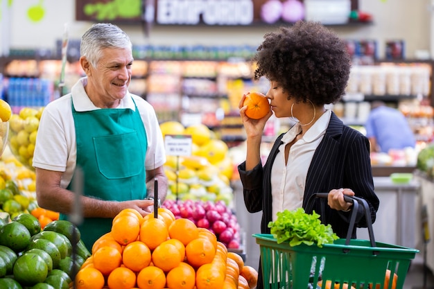 African Customer with greengrocer, holding orange fruit.