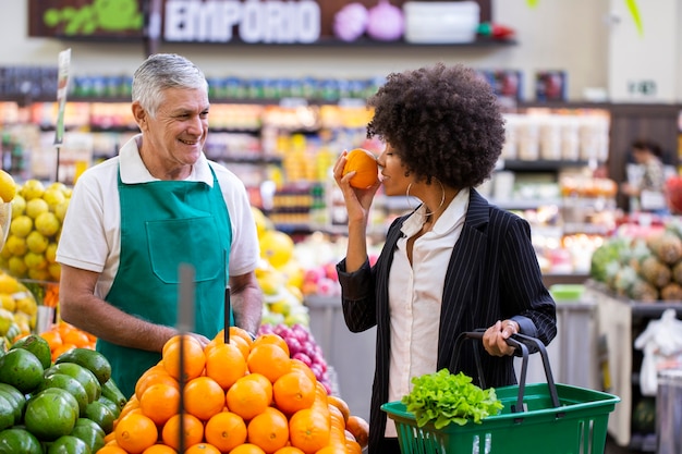 African Customer with greengrocer, holding orange fruit.