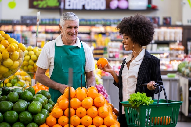 African Customer with greengrocer, holding orange fruit.