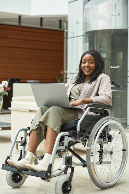 African disabled woman in wheelchair using laptop for online work at office