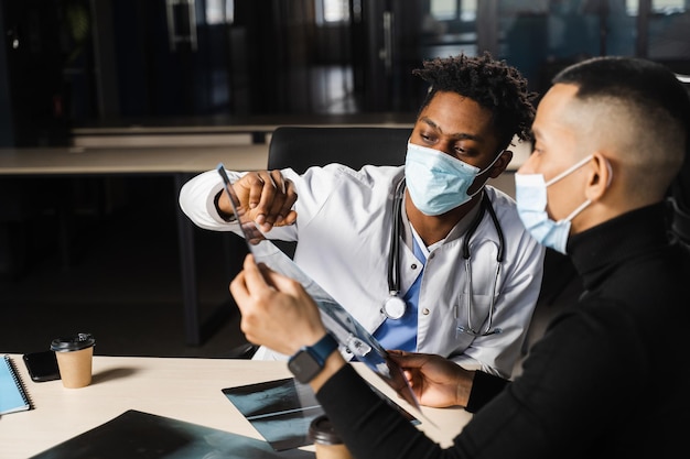 African doctor show xray asian patient Pneumonia and pleurisy Black surgeon analyzing x ray and diagnosis patient in medical clinic