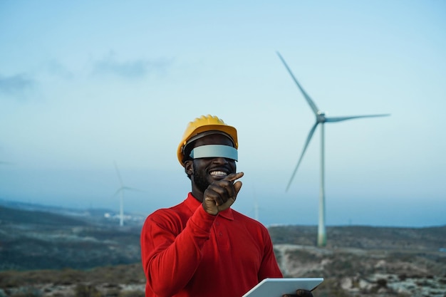 African engineer man using futuristic augmented reality glasses on a windmill farm Focus on hand