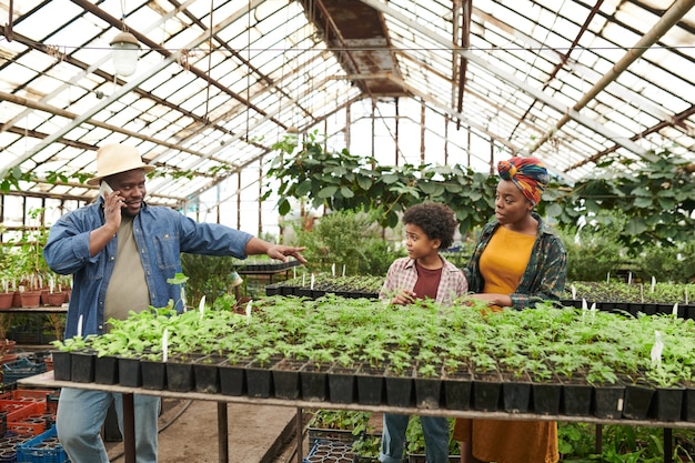 African family of three growing vegetables together in the greenhouse