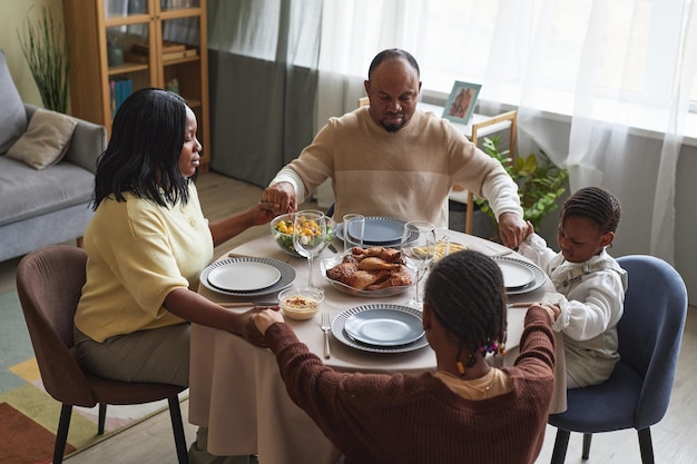 Famiglia africana con bambini che pregano a casa