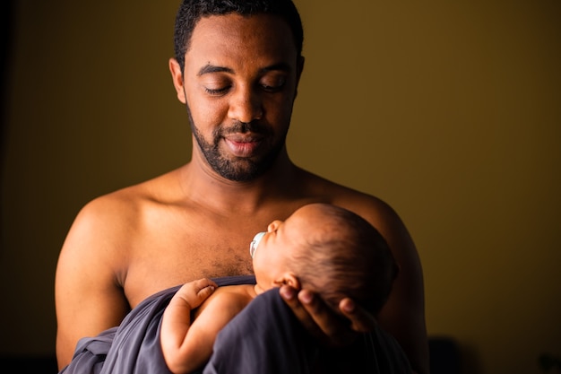 African father from Ethiopia holding with love his baby on olive green background