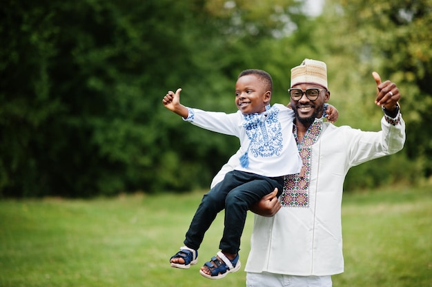 African father with son in traditional clothes at park.