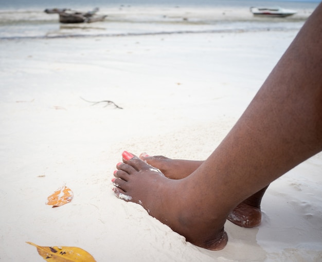 Piedi femminili africani sulla sabbia della spiaggia