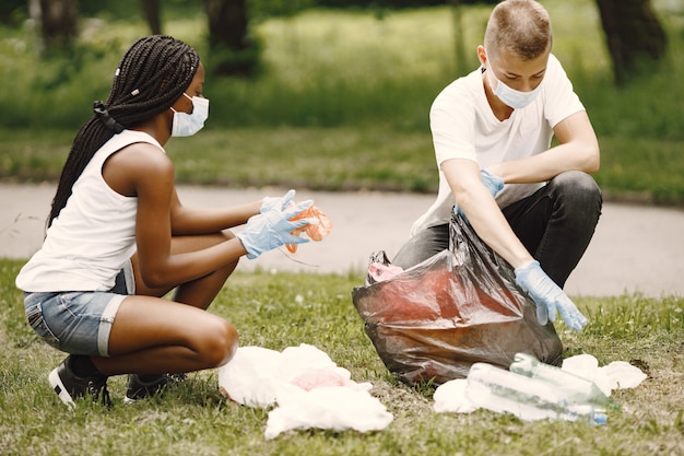 African girl and European boy pivcking up trash. Activists clearing the park sideways.