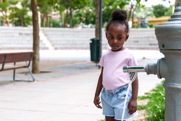 African Girl Grieves Colorful Park Fountain Leaks Trees Surround