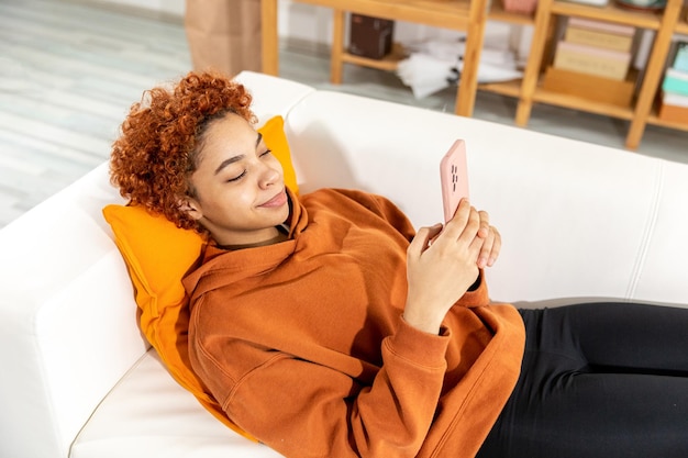 african girl holding smartphone touch screen typing scroll page at home woman with cell phone