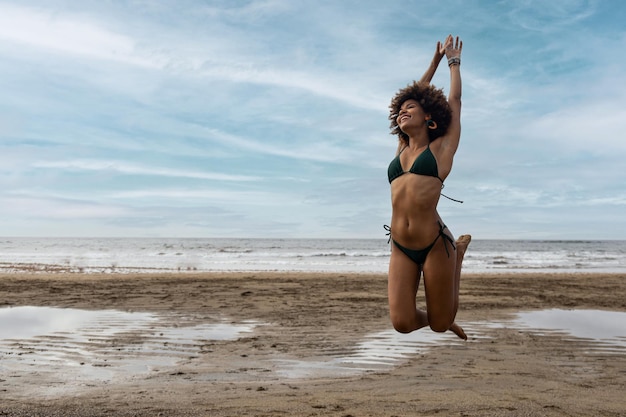 Ragazza africana che salta felice sulla spiaggia