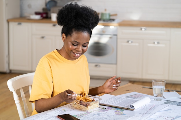 African girl student or freelance businesswoman enjoy pasta for lunch while work from home office