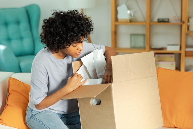 African girl unpacking delivery looking in box happy woman opening carton box female getting parcel