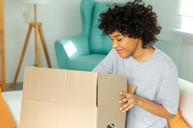 African girl unpacking delivery looking in box happy woman opening carton box female getting parcel