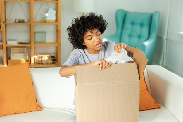 African girl unpacking delivery looking in box happy woman opening carton box female getting parcel