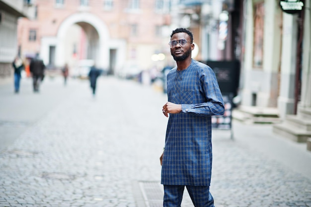 African guy in blue authentic costume, eyeglasses. Fashionable nigerian man.