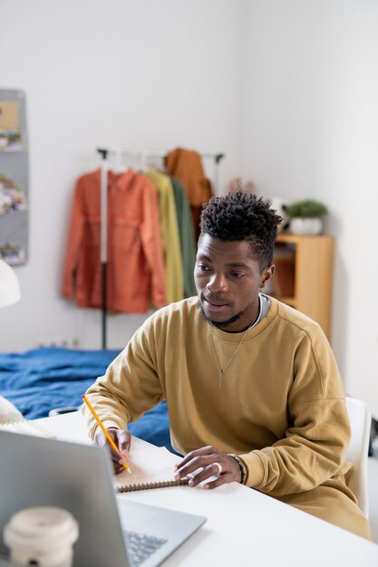 African guy in casualwear looking at laptop display