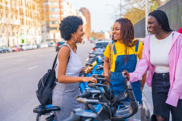 African happy friends renting public bike using phone