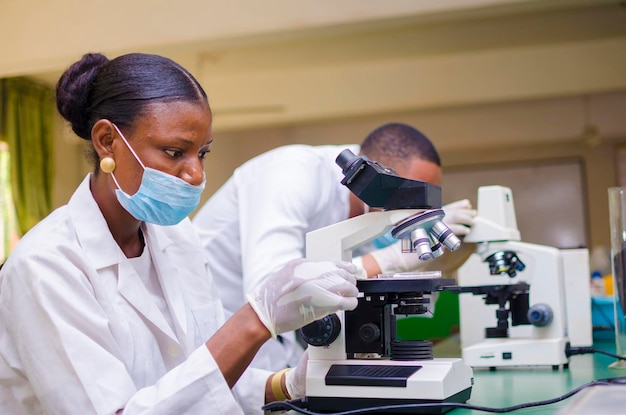 African health care researchers working in life science
laboratory. young female research scientist and senior male
supervisor preparing and analyzing microscope slides in the
research lab