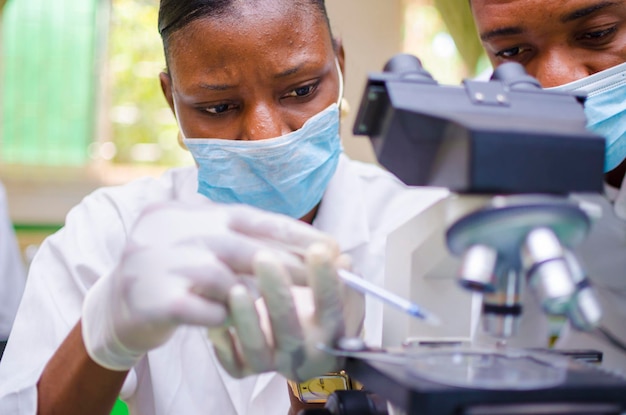 African health care researchers working in life science\
laboratory. young female research scientist and senior male\
supervisor preparing and analyzing microscope slides in the\
research lab