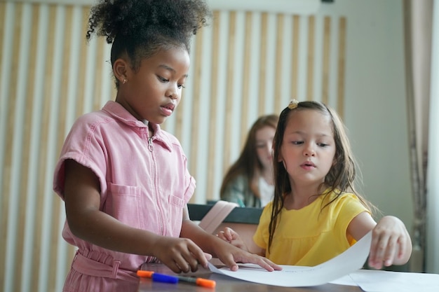 アフリカの子供たちが教室で絵を描いて宿題をする若い女の子学校で幸せな面白い勉強