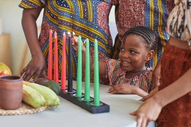 African little child burning candles for kwanzaa holiday to celebrate with her family