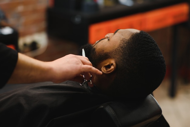 African male client getting haircut at barber shop from professional hairstylist