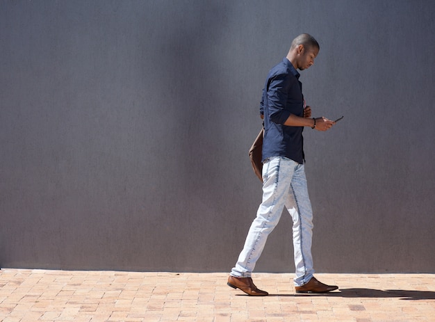 Foto studente maschio africano che cammina con il tablet