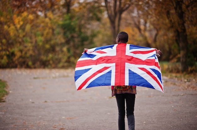 イギリス国旗と秋の公園でアフリカの伝統的なシャツのアフリカ人。