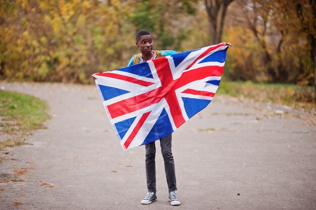 イギリス国旗と秋の公園でアフリカの伝統的なシャツのアフリカ人。